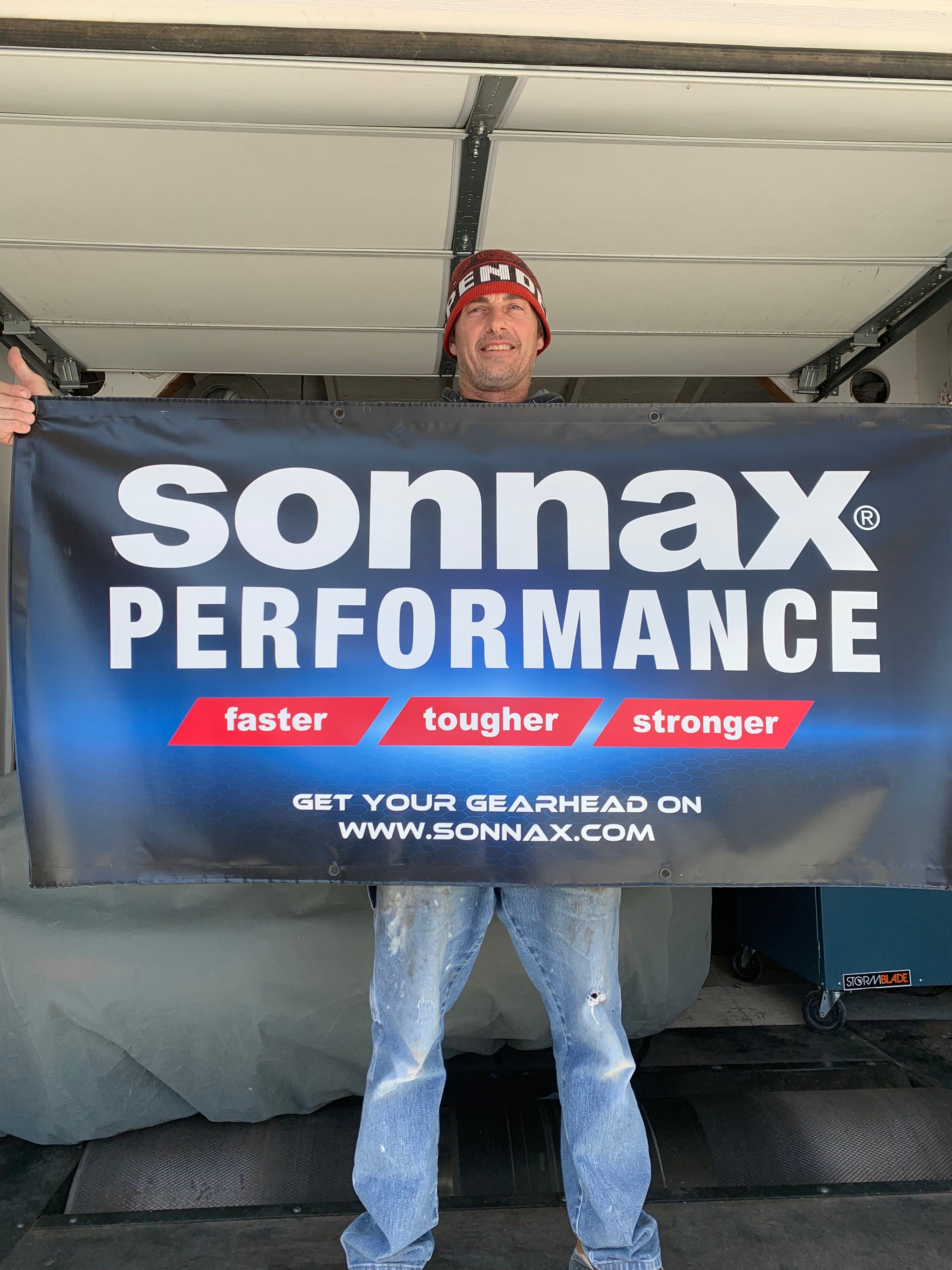 Person standing next to a large blue and red banner with text about performance and strength.