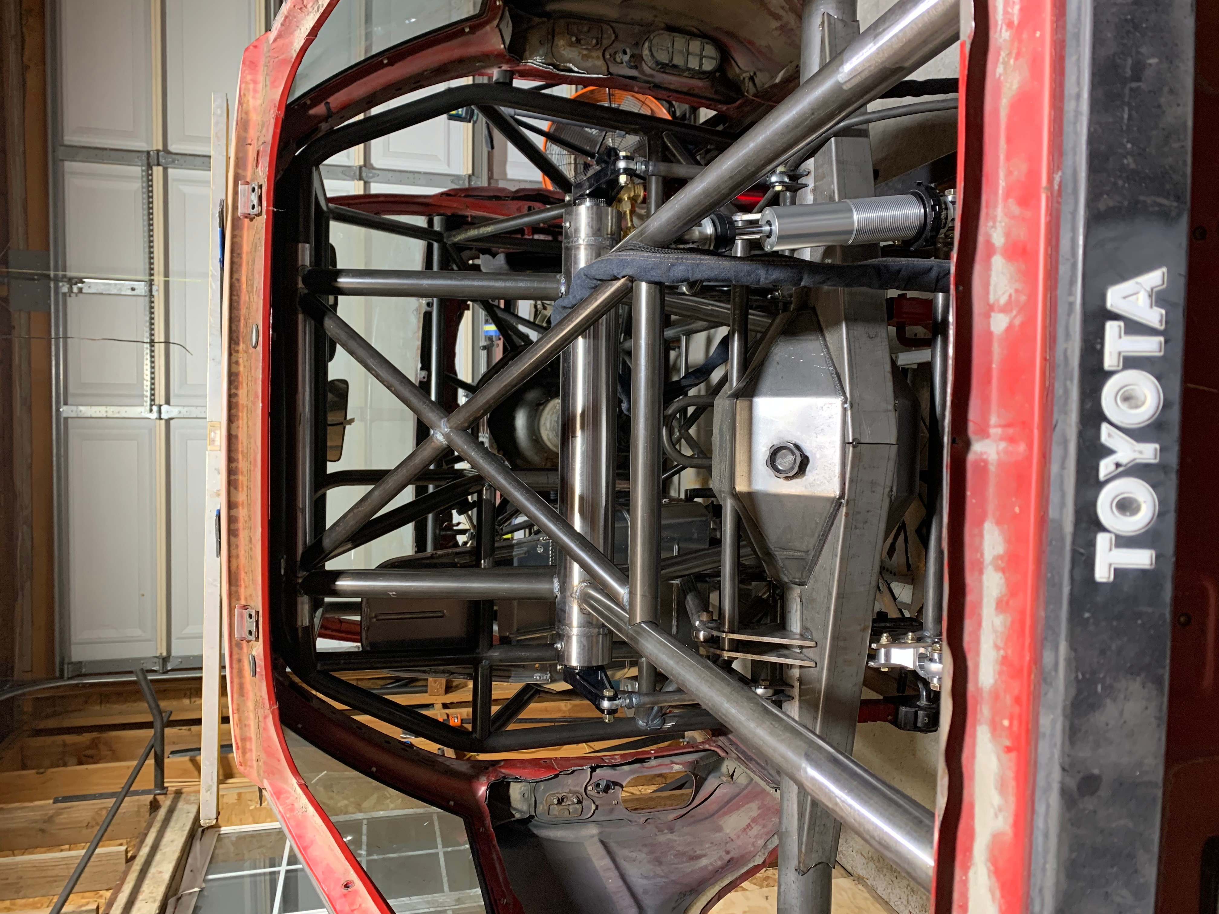 View of the underside of a race car showing suspension and chassis components, with a Toyota logo visible on the side.