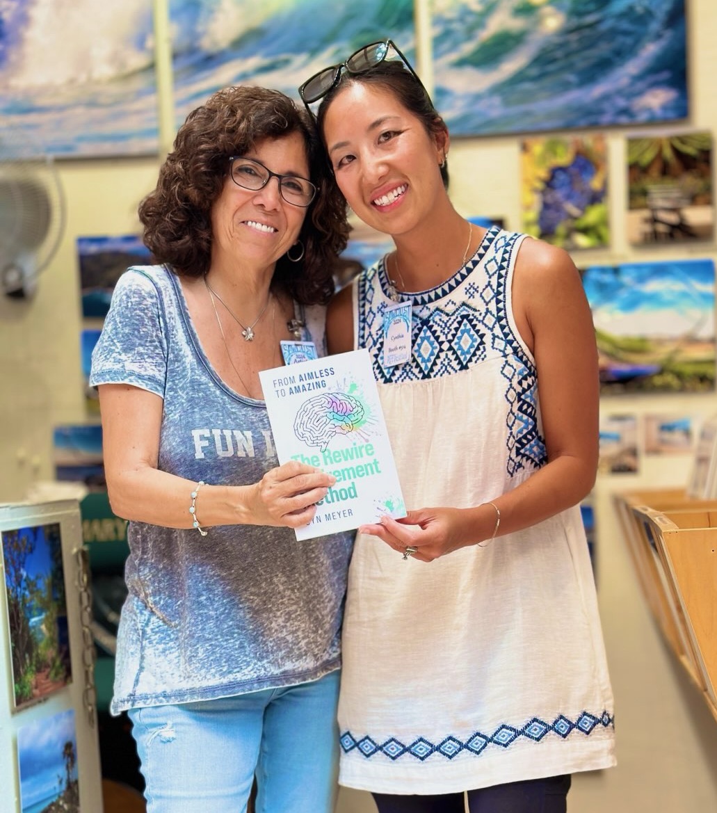 Two women smiling and holding a certificate in an art gallery with paintings in the background.