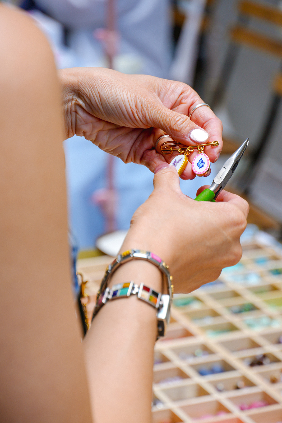 Close-up of hands holding a small object, with a colorful background and a bracelet on the wrist.